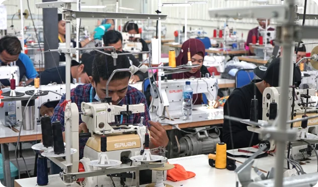 workers operating sewing machines in a modern garment manufacturing facility, producing swimwear